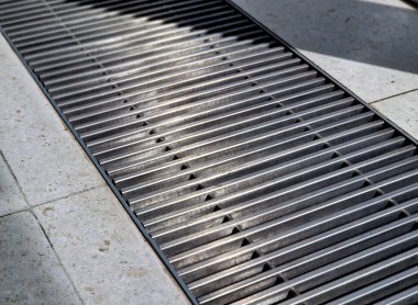 Ofis odasının penceresinin altındaki yerden havalandırma ya da ısıtma egzozu. Her şey zeminin altında saklı. Yüzeyde halı olan hedefler çift katlı. Altında borular var.