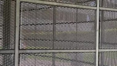 Genişletilmiş metal kafes yapısı olan bir binanın çelik kaplaması. Galvanize gri ağlar endüstriyel binayı koruyor. Gümüş arkaplan ve duvarın aksine mavi gökyüzü
