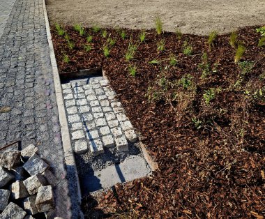 Çakıl taşı yolunun tamiri. Küpün eklemleri arasına asfalt dökülür. Üstünden beyaz silis kumu serpilmiştir. Böylece arabanın tekerleklerine yapışmaz.