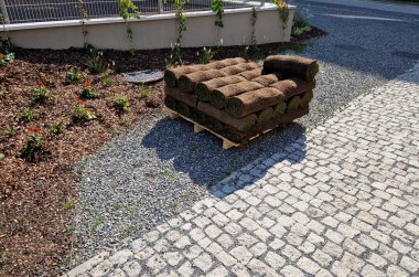 Sipariş için çimen taşıma. Paletler çimenli, halı küçültücü kumaşla kaplı. Bölgeyi güneşin aşırı ısınmasına karşı korur.