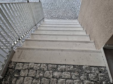 concrete staircase with stainless steel polished tubular railing. cobblestones cobblestones concrete. screwed to the groung, detail