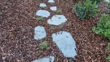 Bahçedeki düz taşlar, ağaç kabuğu parçacıkları ile samanlanmış bir yatak içeren bir patika oluşturur. İki sıra halinde basamaklar ziyaretçileri parka götürüyor.