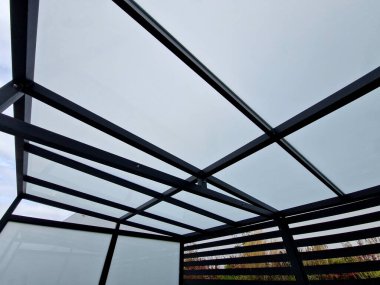 strut, suspended glass roof above the building entrance. bus station, railway station. cable wind braces. aluminum construction with windows above pergola  galvanized steel frame