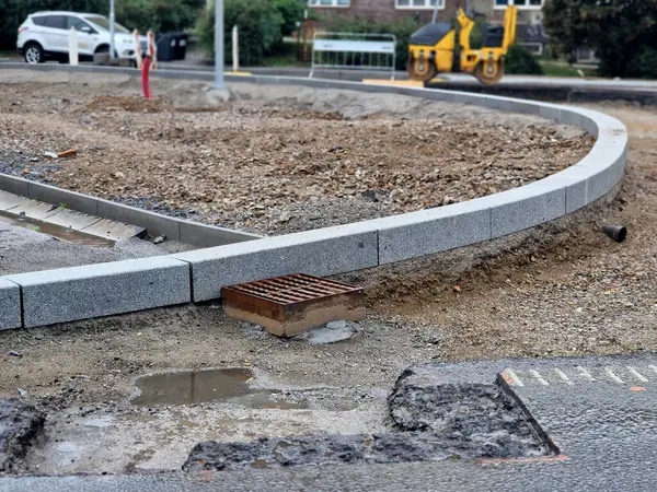 stock image finishing around the roundabout. spreading horticultural soil for lawns for sowing. excavator on the road roller