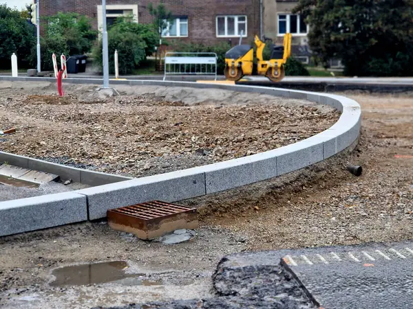 stock image finishing around the roundabout. spreading horticultural soil for lawns for sowing. excavator on the road roller