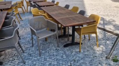Kafe terasında ahşap bir masa ve teneke kutuda bir çiçek. Soğuğa yakalanan ziyaretçileri örtmek için arkada battaniyeler olmalı. Sonbahar terasında kahve, kasaba meydanı.