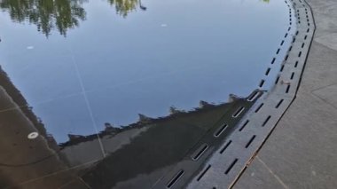 Halka açık alanda zemini kaplayan düşük seviyeli bir çeşme. Su taşkınlığı ızgarası olan bir kanal tarafından kontrol edilir. Serbest bırakıldıktan sonra normal asfalt bir gezinti alanı var. Su birikintisi, dalış havuzu