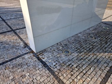 Katı gri desenli hafif afiş. Çiçek tarhında reklam amaçlı bir ilan var..