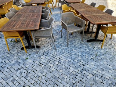 Cafe terrace with a wooden table and a flower in a tin pot. There must be blankets on the back to cover visitors caught in the cold. coffee on the autumn terrace, town square clipart