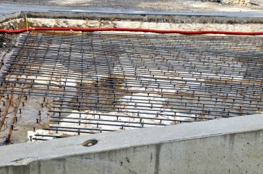 Bir mikser ve hortumla pompa yardımıyla yeraltı garajlarının zeminini somutlaştırmak. Beton takviye kabloları gri bir örgüye dolanmış. Büyük binaların monolitik yapıları