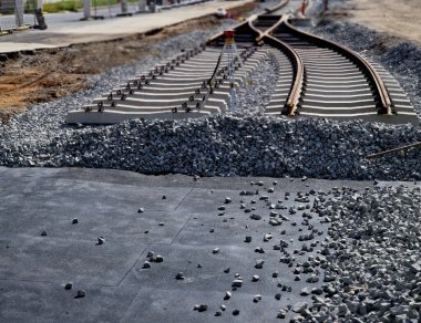 İki tramvay rayında çataldaki seviyelendirme cihazlarını kullanarak yeni ve kesin raylar döşemek. Üstlerine beton örtüler konmuş çakıl taşları... kauçuktan yapılmış kauçuk anti-titreşim tabanı