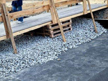 alternative pedestrian route over the bridge under repair. scaffolding and access ramps will guide people through the construction site above the river. orange mesh as a railing over the water