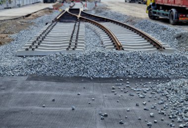 İki tramvay rayında çataldaki seviyelendirme cihazlarını kullanarak yeni ve kesin raylar döşemek. Üstlerine beton örtüler konmuş çakıl taşları... kauçuktan yapılmış kauçuk anti-titreşim tabanı