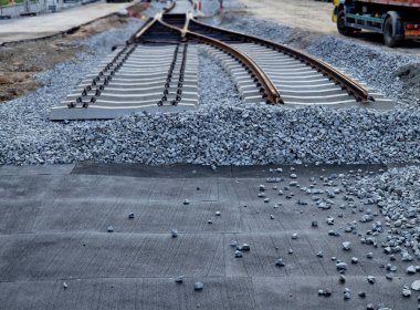 İki tramvay rayında çataldaki seviyelendirme cihazlarını kullanarak yeni ve kesin raylar döşemek. Üstlerine beton örtüler konmuş çakıl taşları... kauçuktan yapılmış kauçuk anti-titreşim tabanı
