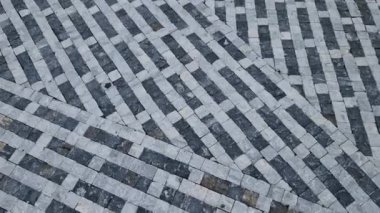 striped white mosaic tile marble. gray stripes sidewalk with walls of gabion baskets around. gray metal garden gate. low fencing for children and dogs. Kindergarten playground