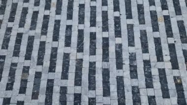 striped white mosaic tile marble. gray stripes sidewalk with walls of gabion baskets around. gray metal garden gate. low fencing for children and dogs. Kindergarten playground