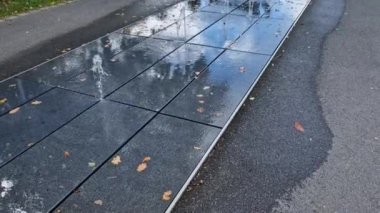 Kaldırımdaki bir şeride yığılmış kare granit kaldırım, sırayla püskürtülmüş su püskürtüleri. - Evet. Su özellikleri doğrudan park sırasındaki kaldırımlı meydandan ortaya çıkıyor. ıslak kiremitler tahta kaldırım