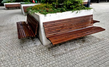 Kare tuğla saksı. Yüzey su geçirmez alçı malayla gerilmiş. Kenarında damlayan bir gölgelik bulunan metal bir levha var. Çiçek yatak kabı duvarına bağlı bir bank. çalıName