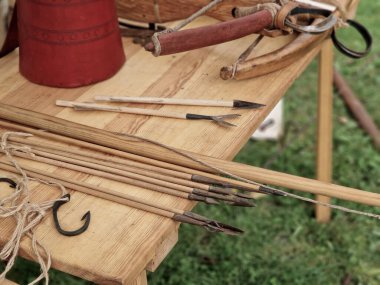Yay ve yaylarla birlikte masanın üzerinde farklı türde oklar var. tendonlar güçlendirildi ve avlanmak için ahşap araçlar