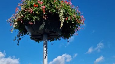 Plastikten yapılmış dekoratif saksıları olan sütunlar. Sepet şeklinde çiçekler asmak, çelenk. Sokak lambalarını ve otoparkları süslüyor.