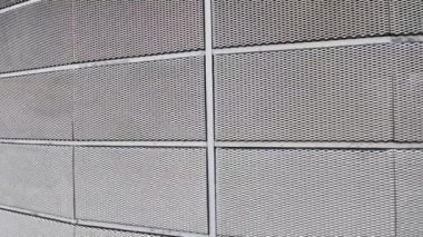 Genişletilmiş metal kafes yapısı olan bir binanın çelik kaplaması. Galvanize gri ağlar endüstriyel binayı koruyor. Gümüş arkaplan ve duvarın aksine mavi gökyüzü