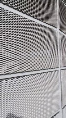 Genişletilmiş metal kafes yapısı olan bir binanın çelik kaplaması. Galvanize gri ağlar endüstriyel binayı koruyor. Gümüş arkaplan ve duvarın aksine mavi gökyüzü
