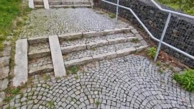 ramp combined with a gray concrete staircase and a handrail specially adapted for wheelchairs. security tasteful solution for entering a city park. sheet metal rails, pram, mother, wheels