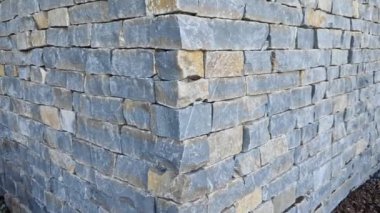 Modern gri kahverengi, bej renkli, metal kapaklı, taş kaplamalı bir ev. Asfalttaki su kanalını boşaltmak için. kireçtaşı kaplama