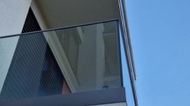 Metal paslanmaz çelik saplarla tutturulmuş cam panellerden oluşan lüks bir evin parmaklıkları. Havalı bir izlenim veriyor. Sera terası penceresinde cilalanmış metal kaplama, yansıma.