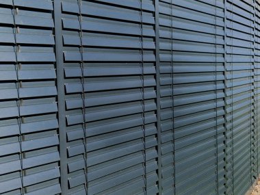 Binalarda panjur servisi. Metal çatalların ayarlanması, ayarlanması ve bakımı. Perdeleri kapalı bir ofis penceresi. Gri metal kapı kapağı. Güneş koruması, dükkan önü, servis