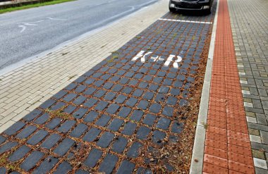 Tabela arabasıyla kaldırım kenarına park edip gezmek. Araba ve toplu taşıma hizmetleri sunar. Bilgilendirici mavi trafik işareti aracı park etme metodunu doğruluyor