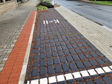 Tabela arabasıyla kaldırım kenarına park edip gezmek. Araba ve toplu taşıma hizmetleri sunar. Bilgilendirici mavi trafik işareti aracı park etme metodunu doğruluyor