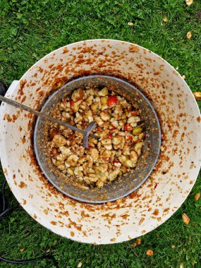 Düşen elmalardan elma suyu yapmak vidayla baskı uygulamak çocukların elma suyunu hasırdan elek yoluyla çıkarmasına yardımcı olur ve hamuru gübreye atar.