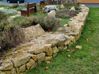 Bir çiçek tarlasında merdivenleri olan kumtaşı duvarlar ve taşlar. Çiçekli kaya bahçeleri ve çakıl yüzeyi olan merdivenler. Bitki bahçesi, kış, yamaç, duvar graniti.