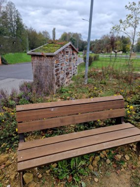 Taş ve ahşap dolu eski paletlerden yapılmış böcek oteli. Sigorta kutusunun yanında yosunlu ve sulu yeşil çatı.