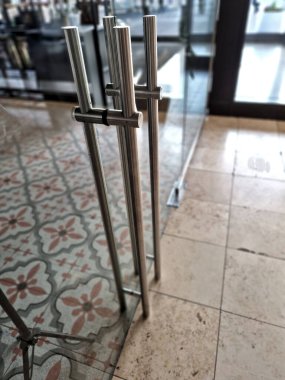 Çerçevesiz cam kapı. Camlı bölmelerin özel menteşeleri ve sapları vardır. Her şey cama kazınır ve paslanmaz çelik vidalarla tutturulur. parlatılmış bar kolu, kırmızı, 