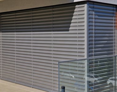 Metal paslanmaz çelik saplarla tutturulmuş cam panellerden oluşan lüks bir evin parmaklıkları. Havalı bir izlenim veriyor. Sera terası penceresinde cilalanmış metal kaplama, yansıma.