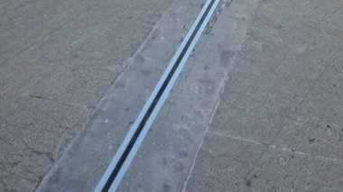 İki genişletilebilir beton gövdenin güvenli bağlantısı için çatı yapısı veya köprü genişlemesi. Metal bir barda lastik eklem, çatlak, aşınmış, video, kaldırım, yenileme, don, tuz, çatlak, ezilmiş