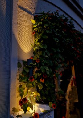 spot wall light illuminates the wall of facade of house in a conical shape at night. evening positioning and navigation lamp of black color shines in two directions on gabion wall, powder coated paint clipart