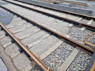 precise laying of tracks using leveling devices at the fork in two tram tracks. a layer of gravel above which concrete sleepers are placed. rubber anti-vibration base made of rubber, edgeinsreuction clipart