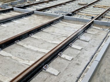 Çataldaki iki tramvay rayının seviyelendirme aletlerini kullanarak rayların tam döşenmesi. Üstlerine beton örtüler konmuş çakıl taşları... kauçuktan yapılmış kauçuk anti-titreşim tabanı.