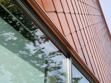 Evin duvarlarını kaplayan bronz fayanslar, balık pullarına benzer kareler. Parlak lüks. Pencereleri gri çerçeveli modern endüstriyel bina. Merdiveni olan iskele.