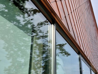 Evin duvarlarını kaplayan bronz fayanslar, balık pullarına benzer kareler. Parlak lüks. Pencereleri gri çerçeveli modern endüstriyel bina. Merdiveni olan iskele.