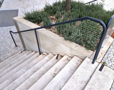 Kalkmış betondan yapılmış bir yatakla bölünmüş geniş bir merdiven. Tırabzanda borulardan yapılmış saplar ve paslanmaz çelik ağ kablosundan yapılmış bir ip var.