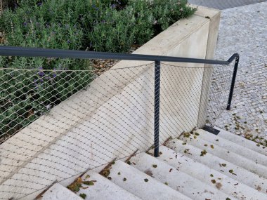 a wide staircase divided by a raised bed made of cast concrete. The handrail has handles made of pipes and a string made of stainless steel mesh cable clipart