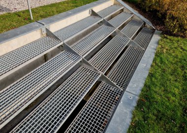 Metal merdivenler geniş ve şeffaf. Paslanmaz çelikten yapılmış. Park için uygun. Merdiven, doğa parkının kaldırımına, kahve masası ve sandalyeli bir terasa bağlanıyor.