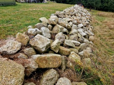 landscaping in the countryside using an excavator. Retaining walls made of massive large boulders dry-stacked into the slope. around cuts of highways, roads and train lines