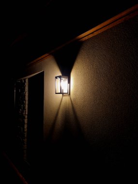 glass lamp on the wall of a house with a beige facade. it shines with warm shades on the wall and forms a cone. reminds of the old days, cemetery clipart