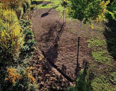 Otomatik sulamanın ardından hasarlı çimlerin onarılması. Toprak yığınları getirip tırmıklarla dağılıyorlar. çimenlik ekme ve oyma.