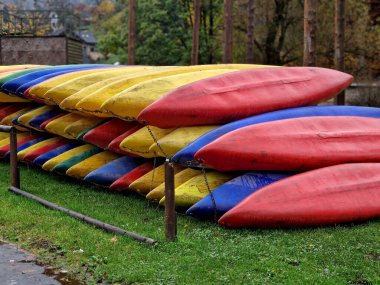 Nehir kıyısında plastik tekne kiralamış. Mevsim dışı ya da kötü havada tekneler zincirlenip yığılır. Hasarlı kanolar tamir ediliyor